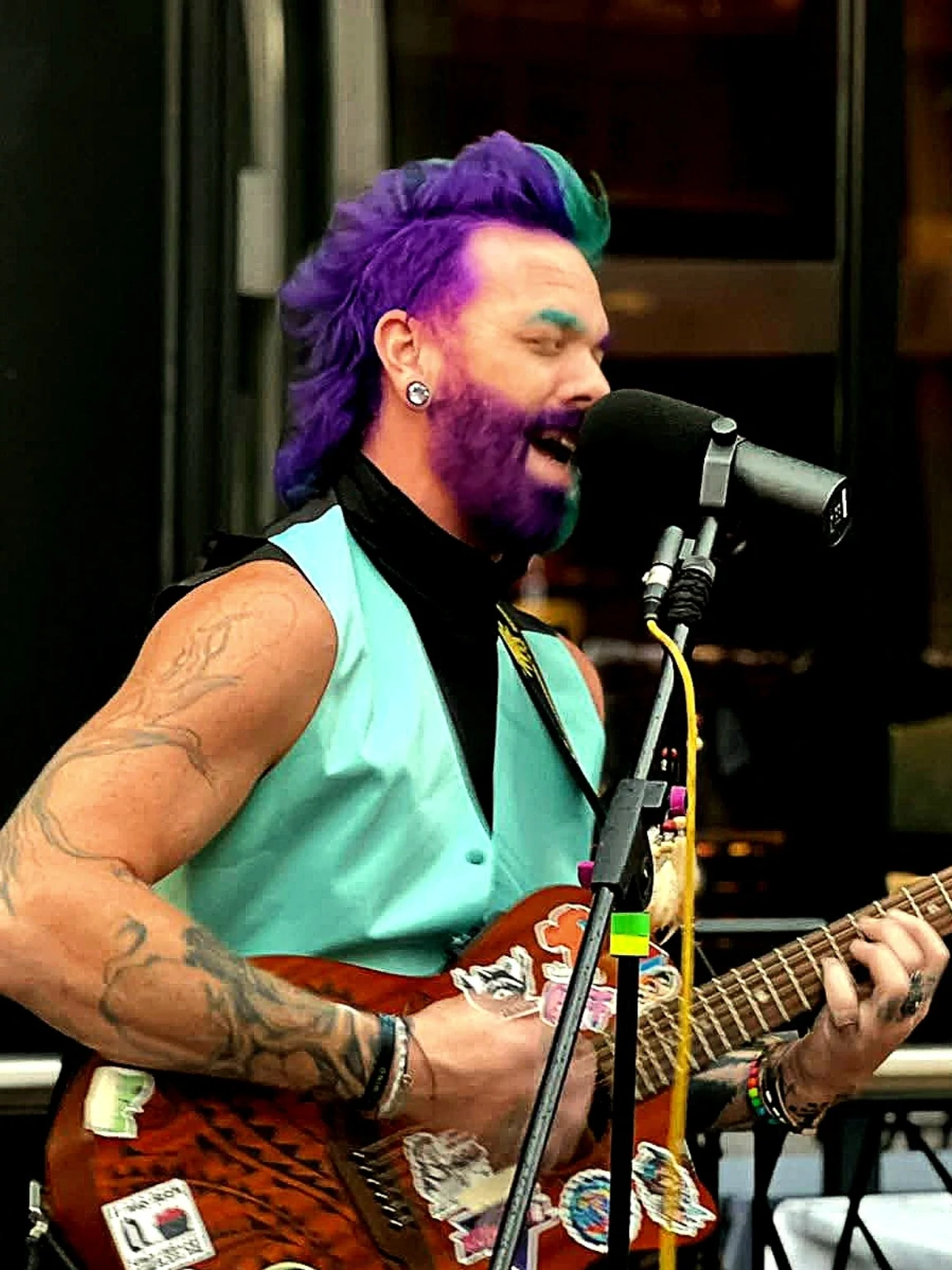 Seth Bonnell performing live with purple hair and an acoustic guitar